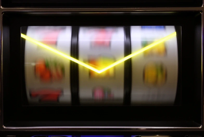 Mid-spin on the letsbuild cabinet, three reels blurred and the V-line payline highlighted in yellow